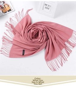 Detail of pink cashmere scarf featuring soft fabric texture and decorative long tassels