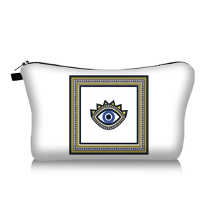 Detail of white travel makeup bag featuring blue evil eye print and black zipper closure