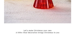 Close-up of red faceted glass Christmas ornament reflecting soft festive lights on a white surface