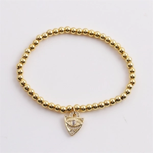 Macro shot of gold-plated beaded bracelet with sparkling zircon evil eye heart charm
