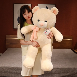 Detail of a large cream teddy bear with a pink bow held by a model to show size scale