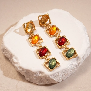 Detailed shot of vintage gold earrings with colorful resin stones on a stone base