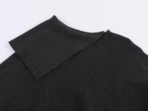 Macro-opname van de antracietgrijze gebreide poncho met fijne ribstructuur en naden