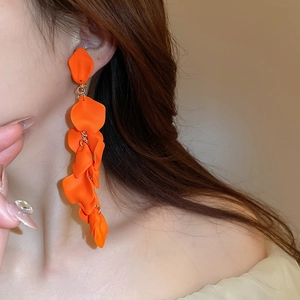 Detail showing long orange petal tassel earrings with golden rings on model