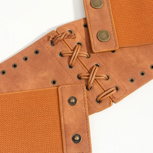 Close-up of brown faux leather waist belt featuring decorative cross-lacing and metal eyelets