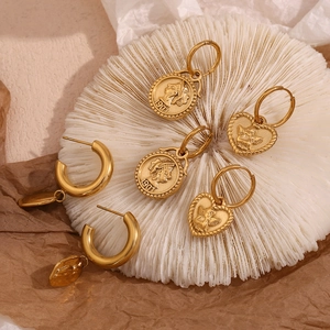 Detail of vintage 18K gold plated earrings set with coin and angel heart designs