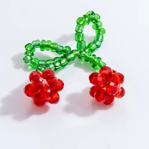 Macro detail of handmade beaded cherry pendant with red crystal and green bow accent