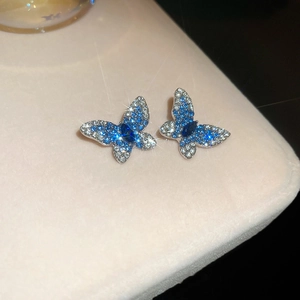 Gros plan de boucles d'oreilles papillon avec cristaux bleus et blancs sur velours