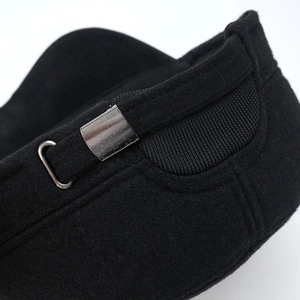 Detail of adjustable gunmetal buckle and elastic band on black wool flat cap