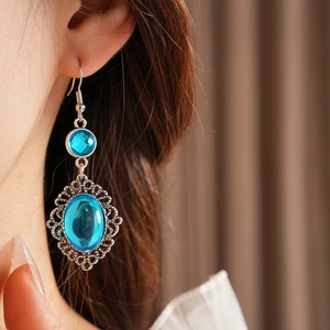 Macro detail of vintage silver earrings with blue resin stones worn by a model