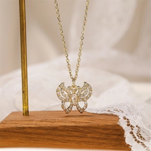 Close-up of golden butterfly pendant with sparkling white zircons on a lace background