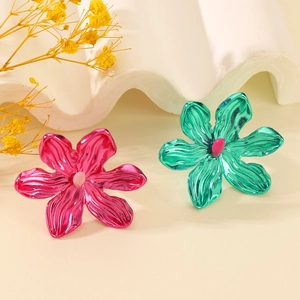 Close-up of vibrant rose pink and emerald green hollow metal flower rings with wavy texture
