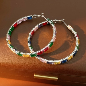 Macro shot of colorful baguette-cut zircon hoop earrings on a brown leather box