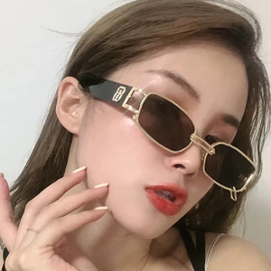 Close-up of golden rectangular sunglasses with metallic logo detail on the temples