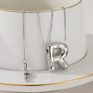 Detailed shot of a silver letter R pendant with cubic zirconia on a fine box chain