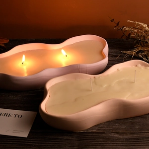 Bougie parfumée en céramique nuage rose avec double mèche sur table en bois noir