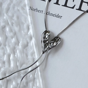 Detail of silver liquid metal heart pendant with lava texture on snake chain