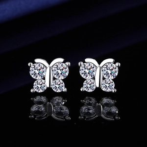 Macro shot of silver butterfly stud earrings with sparkling crystals on black surface