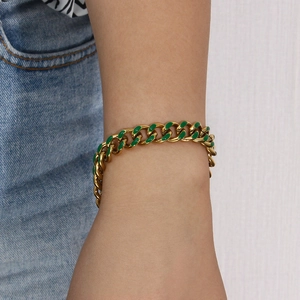 Close-up of golden Cuban link bracelet with green enamel inlay worn on wrist