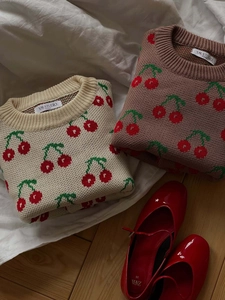 Flat lay of vintage cherry knit sweaters in beige and brown with red patent shoes