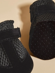 Detail of black breathable mesh dog shoes with non-slip soles and velcro straps