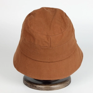 Close-up of brown cotton sun hat with stitching details on dark wood display stand