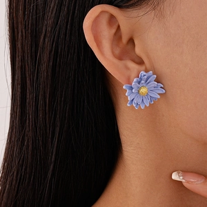 Close-up of purple daisy stud earring with gold pistil on model's earlobe