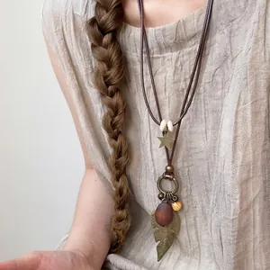 Detailed view of ethnic necklace featuring metal leaf and wooden beads on cord