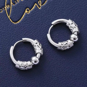 Detailed close-up of silver steel hoop earrings with engraved dragon relief charms