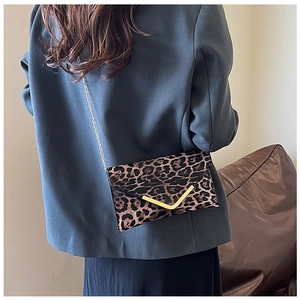 Detail of leopard print crossbody bag with gold V-trim and fine metal chain strap