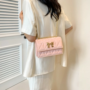 Rosa gesteppte Schultertasche mit goldener Schleife und Kette an einem Model