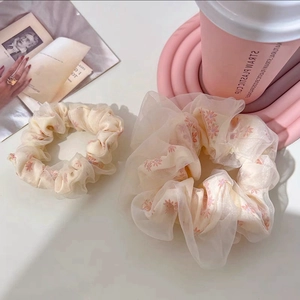 Detail of floral chiffon scrunchies in two sizes with soft pink petal patterns