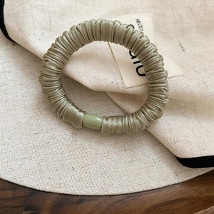 Detail of olive green pleated satin hair scrunchie with elegant resin bead accent