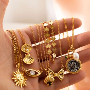 Detailed shot of gold plated sun, shell, and evil eye necklaces with pearls