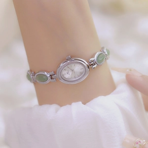 Close-up of silver-tone ladies' watch with green jade-style stones on female wrist