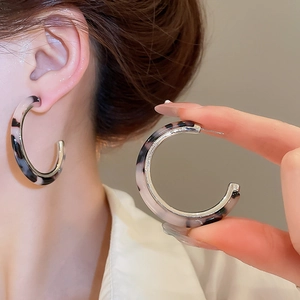 Close-up of C-shaped resin earrings with colorful marble texture and silver metal inlay