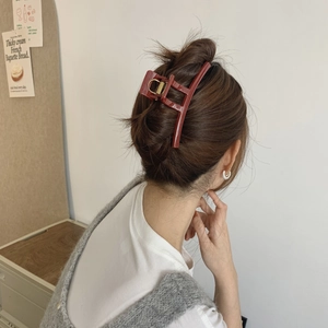 Detail of a large glossy dark red hair claw clip used for a French twist hairstyle
