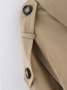 Detailed macro view of khaki trench coat shoulder straps and marble texture buttons