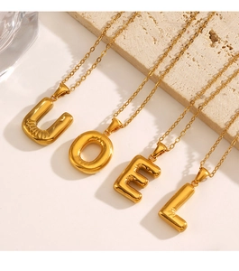 Detailed close-up of 3D balloon style gold letter pendants on dainty link chains