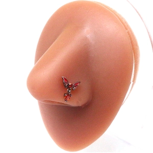Red bat nose stud with heart pendant jewelry piece on a human model's nose