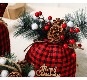 Detail of red and black buffalo plaid Christmas gift bag with pine cones and berries