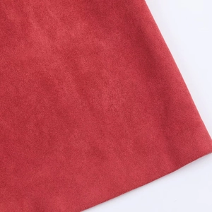 Detailed close-up of red suede fabric texture with a soft matte finish for casual jackets