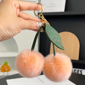 Cute peach-pink rabbit fur cherry keychain with green faux leather leaves and gold ring