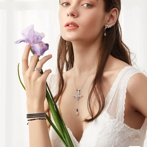 Model wearing silver necklace, earrings and ring set with dark beaded bracelet detail