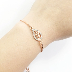 Detail of a golden leaf-shaped bracelet with small sparkling crystals on a wrist