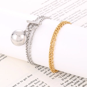 Detail of silver OT buckle bracelet with ball pendant and gold chain on book pages
