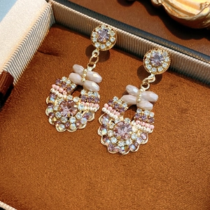 Detail of vintage round rhinestone earrings with purple crystals in a velvet jewelry box