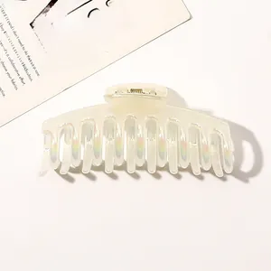 Macro shot of large pearl white hair claw clip with iridescent finish on white background