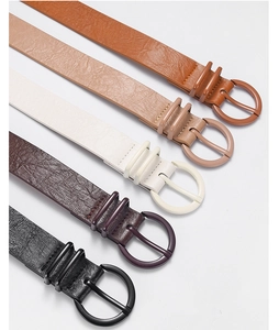 Close-up of five colored faux leather belts with matching round buckles on grey background