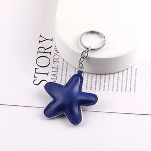 Close-up of a blue leather star charm with visible stitching and silver metal keychain ring